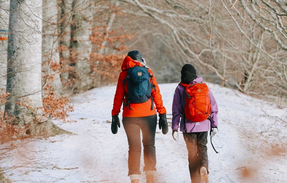 En kvinna och barn som går längs med en skogsstig under vintern.