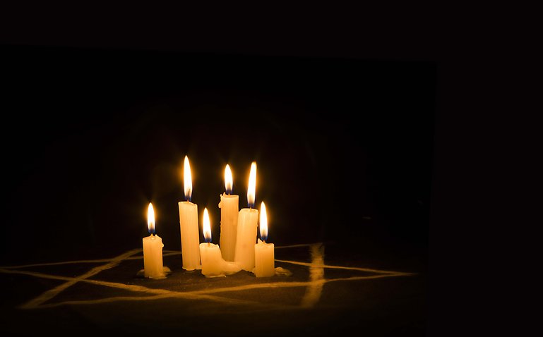 Kupade händer med ljus, till minne av Förintelsens offer.