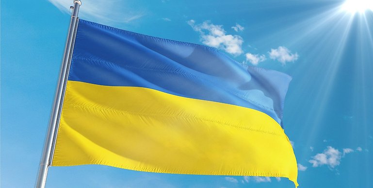 En hissad Ukrainsk flagga mot blå himmel