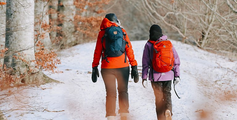 En vuxen och barn som går längs med en vandringsled under vintern.