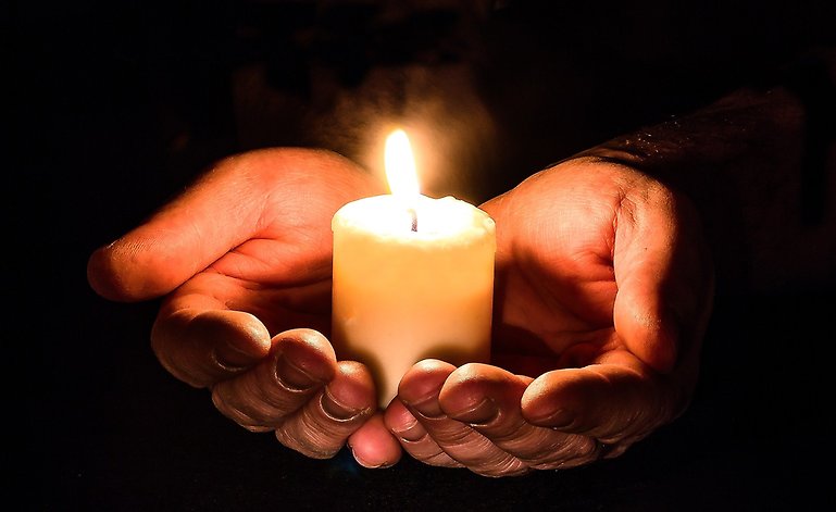 Kupade händer med ljus, till minne av Förintelsens offer.