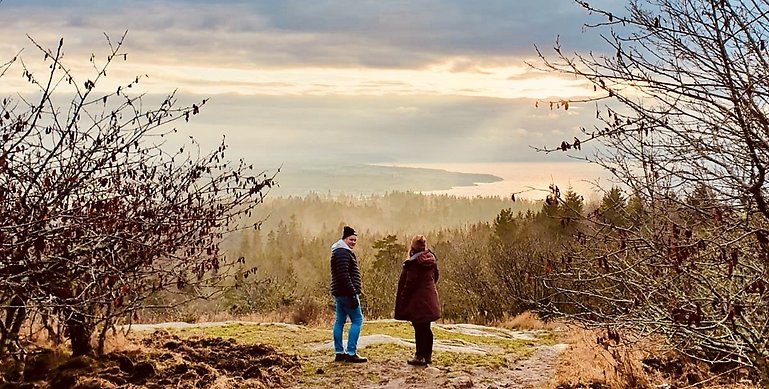 Två personer som står på Hjässan, Ombergs högsta punkt och blickar ut över utsikten. 